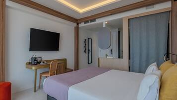 Ein modernes Hotelzimmer mit Bett, Schreibtisch, Sessel, Fernseher und einem großen Spiegel.