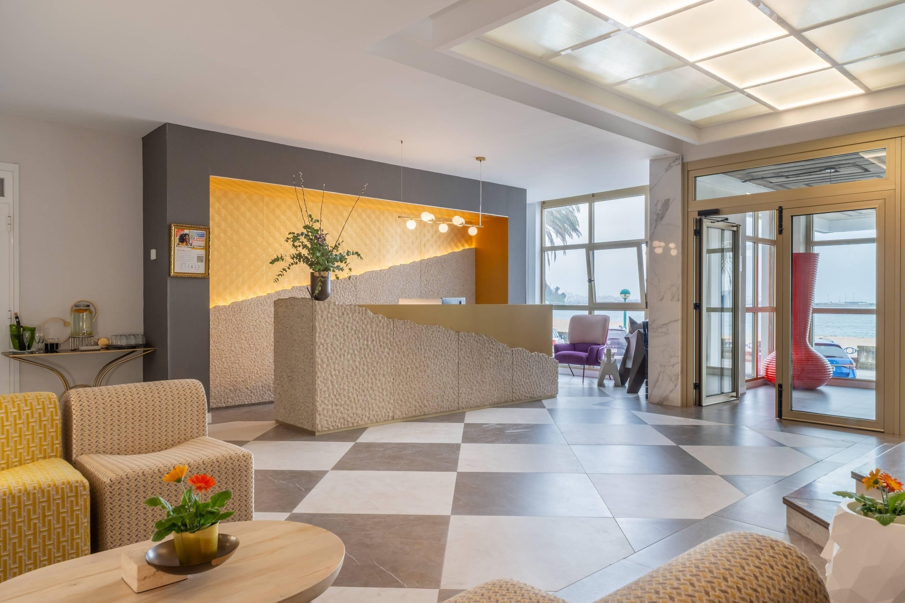 A hotel lobby with a reception desk, seating area, and large windows offering a view.