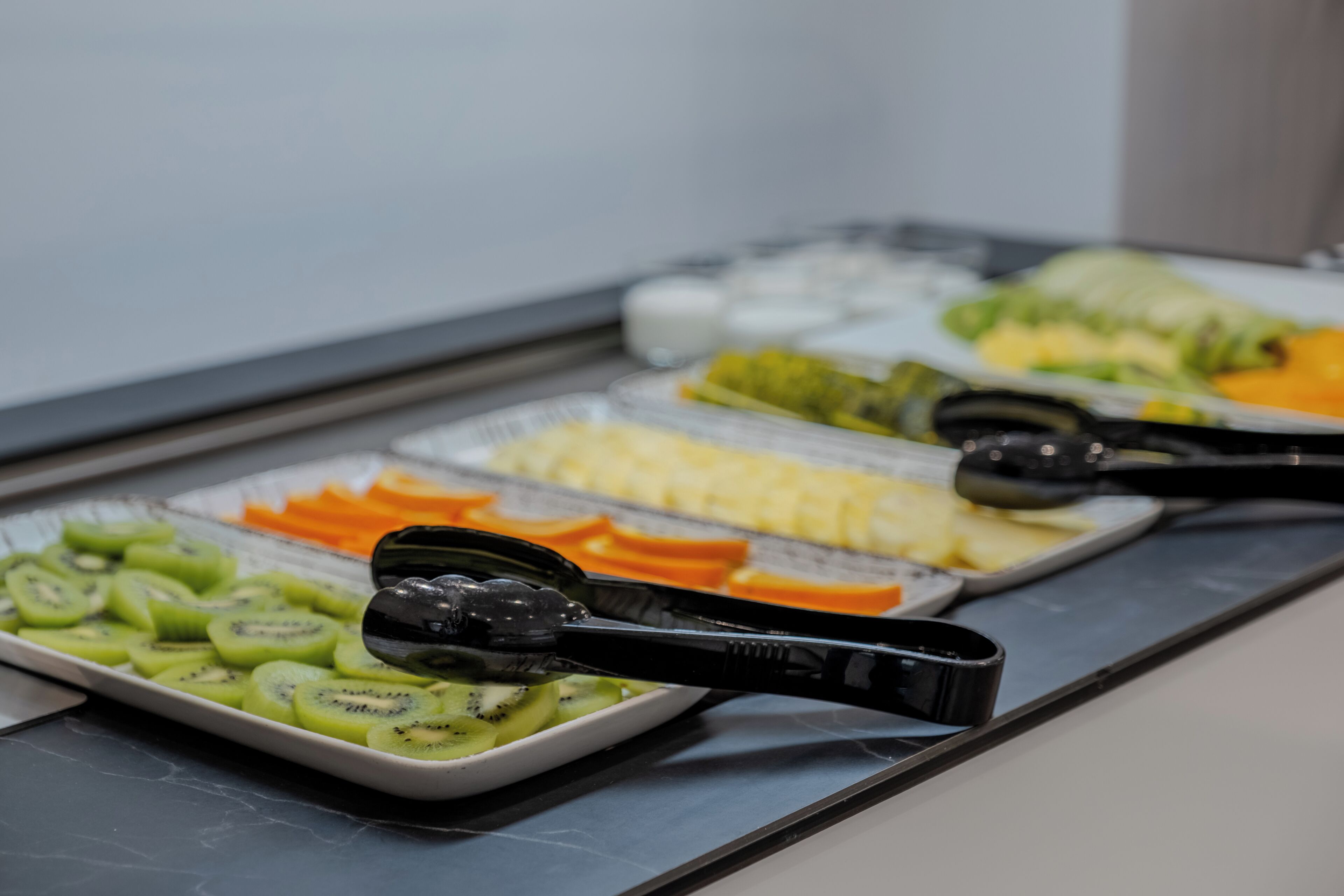 Un bufé con diversos alimentos, entre ellos frutas y verduras cortadas.