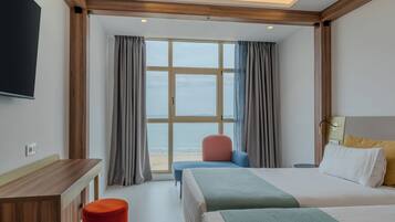 Una habitación de hotel con un ventanal grande, una cama, un escritorio y una silla.