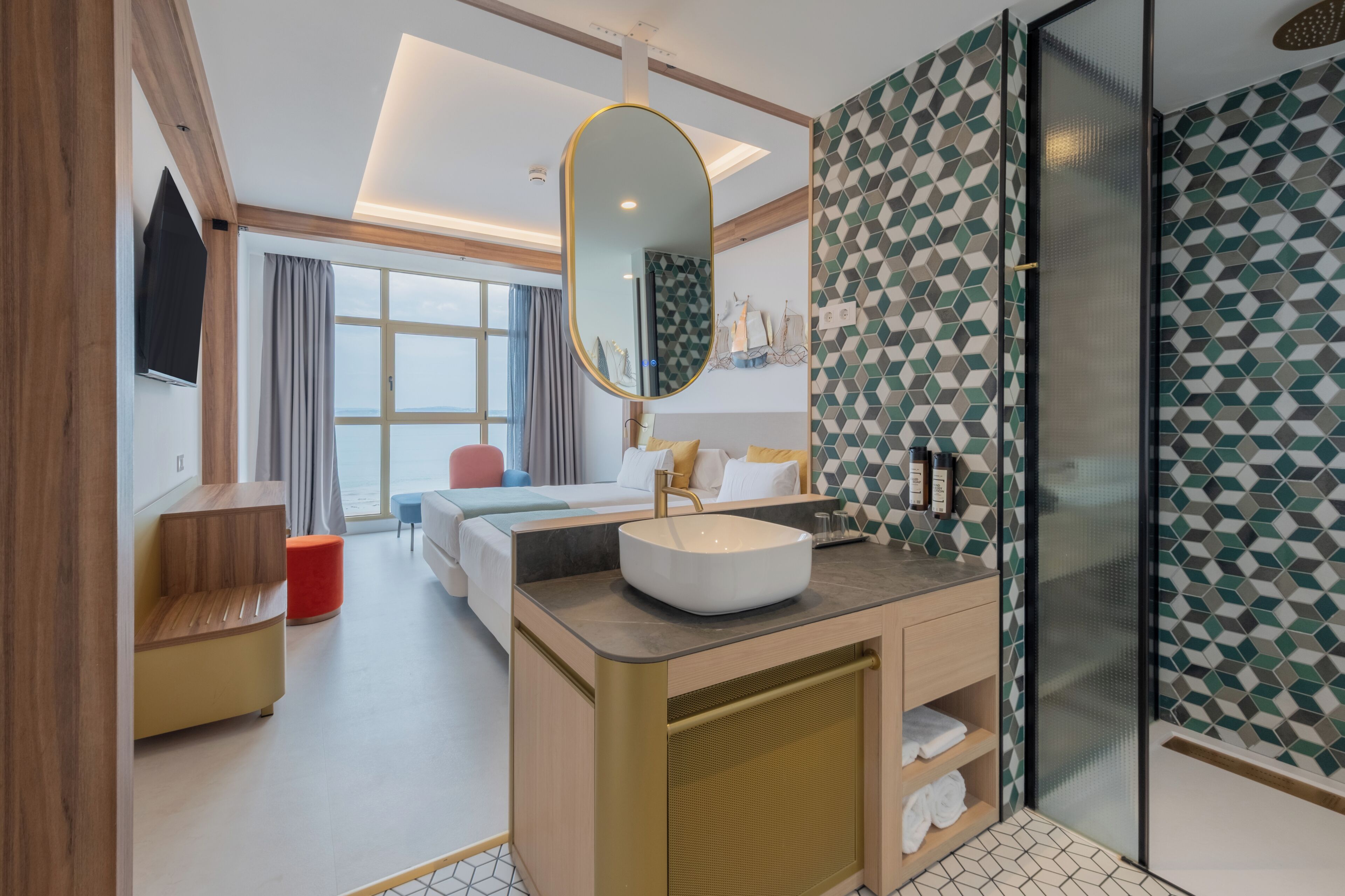 Een moderne hotelkamer met een groot bed, een badkamer met wastafel en spiegel, en een douche.