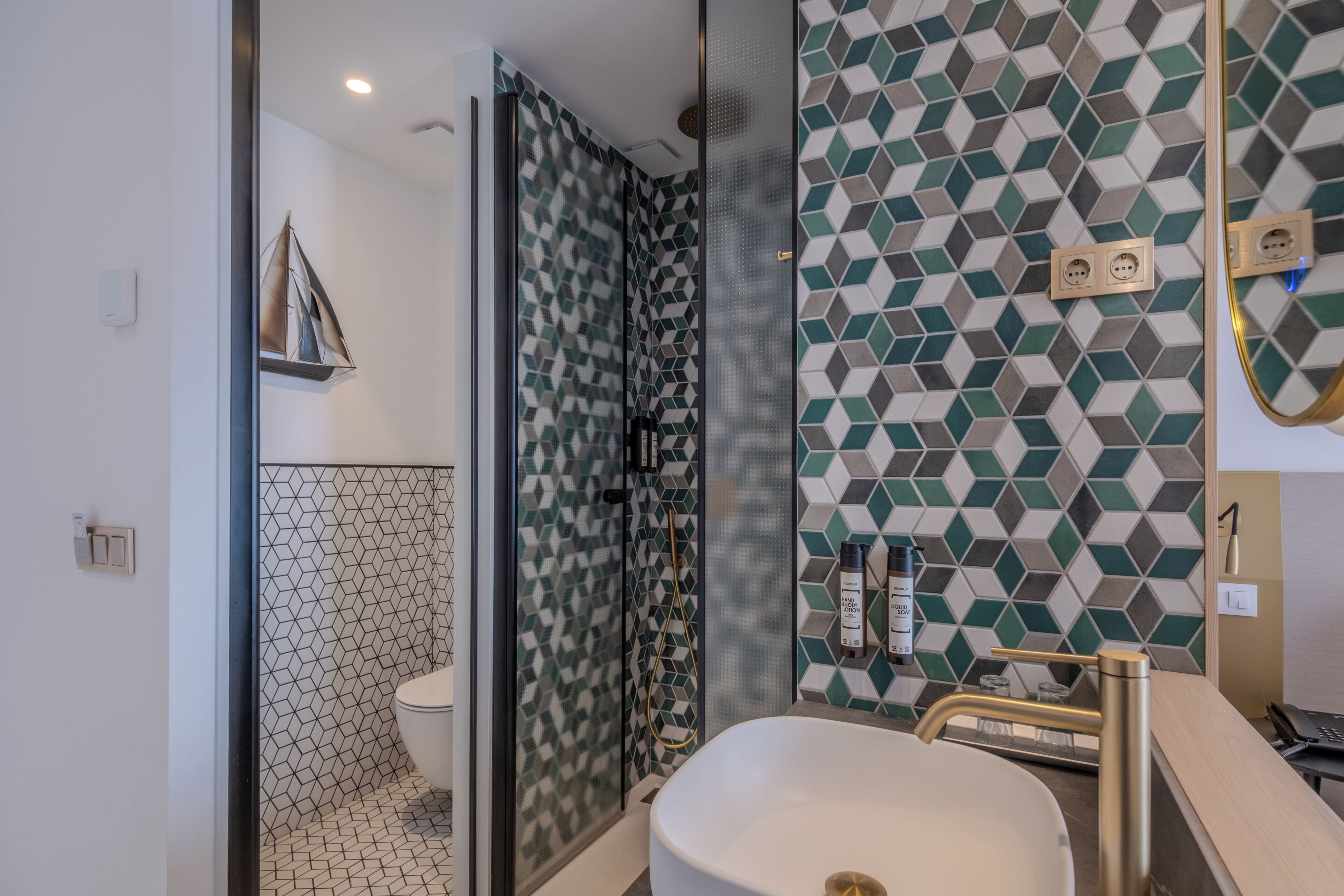 Un bagno con cabina doccia in vetro, un lavandino bianco e carta a parete decorata.