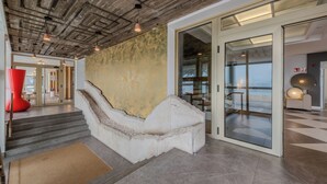 A modern interior with a concrete ceiling, a unique white bench, and a glass door leading to a balcony with a view. - Hotel Faranda Rias Altas, Ascend Hotel Collection (Oleiros)