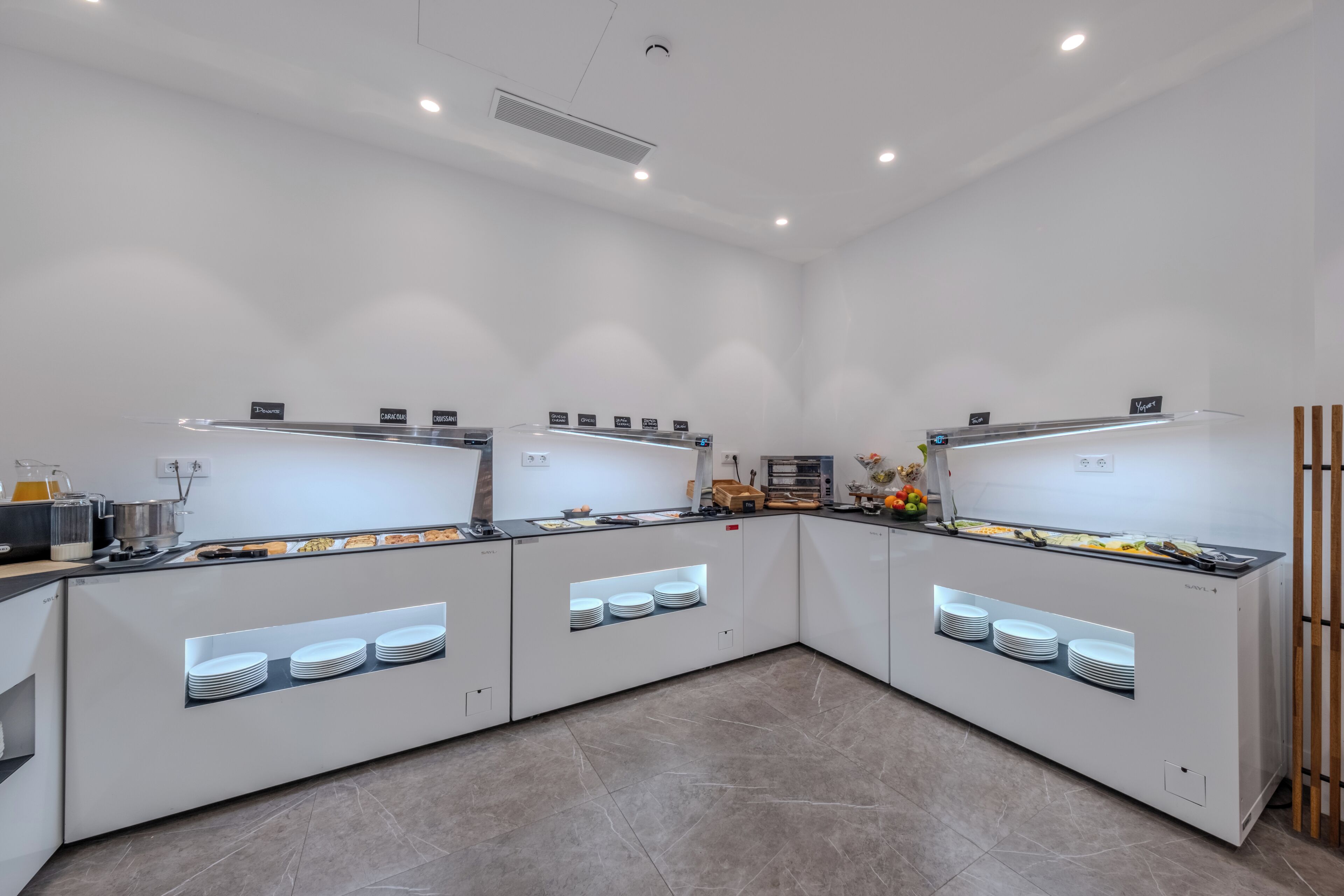 Una cocina moderna con armarios blancos, una isla central con estufa integrada y diversos alimentos expuestos en la encimera.