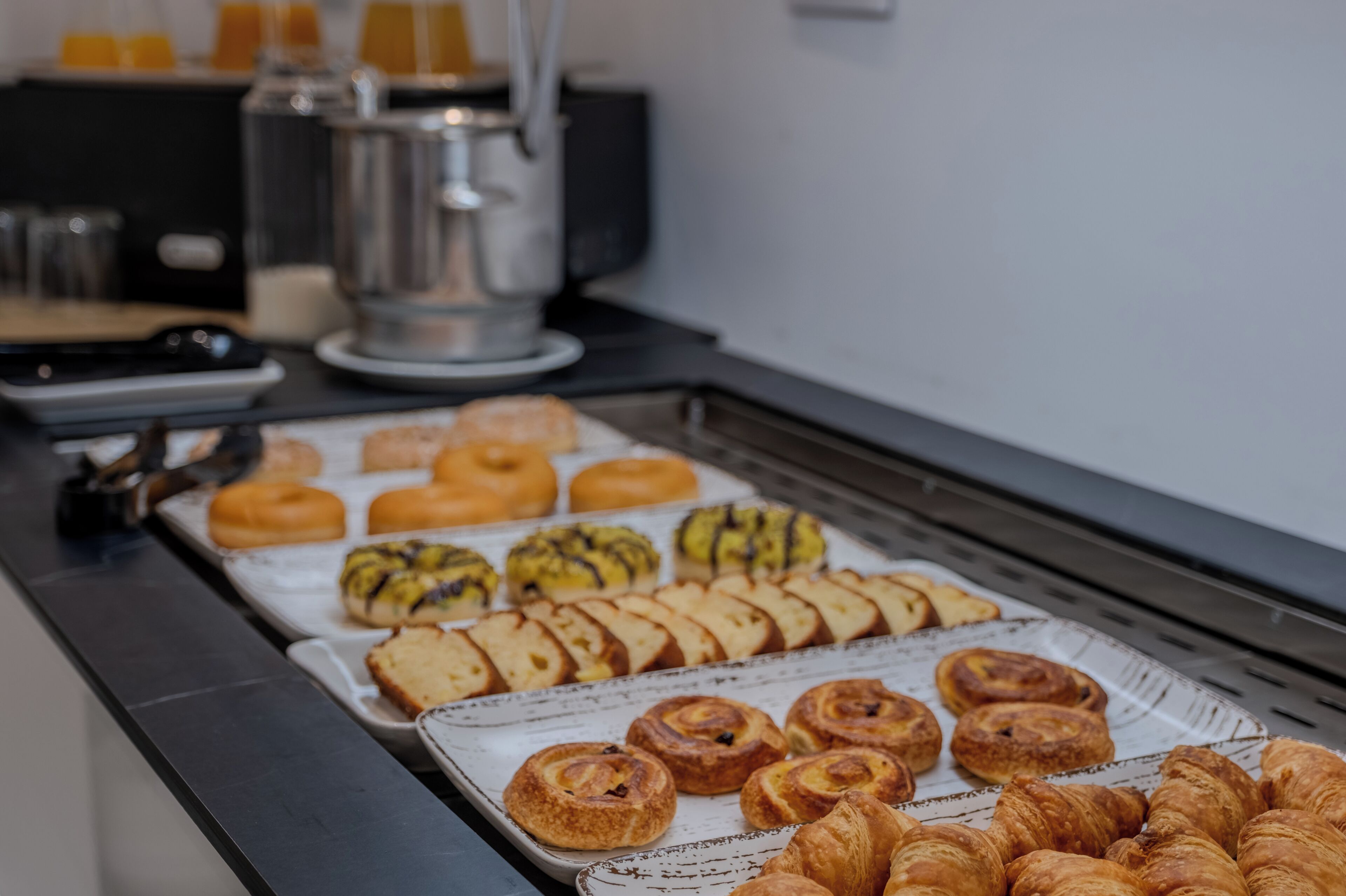 A buffet with various pastries and bread, a coffee machine, and a water dispenser.