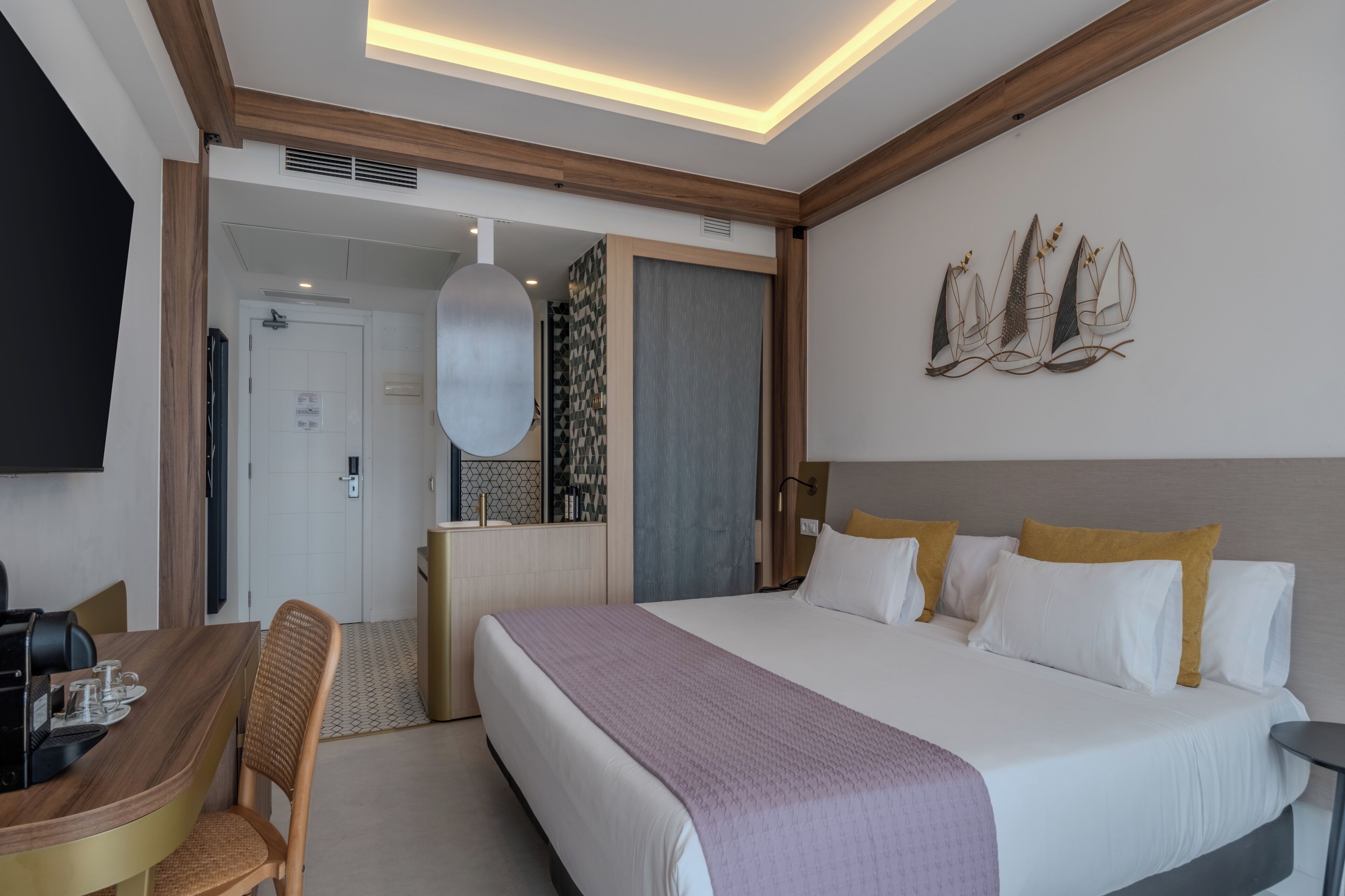 Habitación de hotel con cama, escritorio, silla, televisor y una obra de arte en la pared.