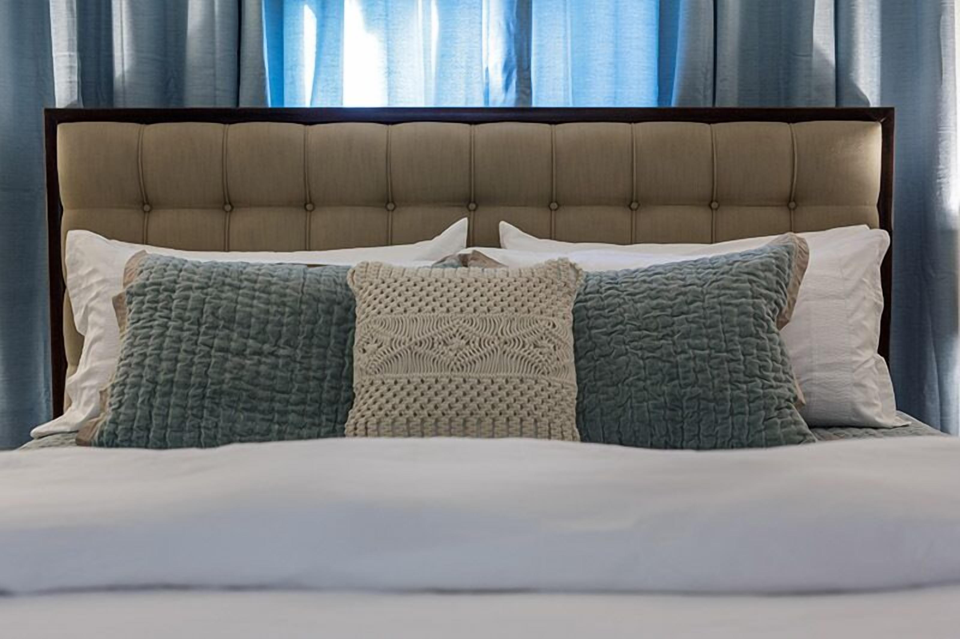 A bed with a tufted headboard, two pillows, and a blanket.