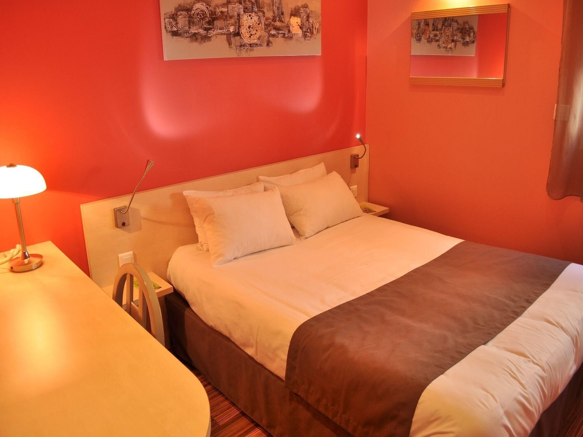 Une chambre d’hôtel avec un lit, une table de chevet, une lampe et une œuvre d’art au mur.