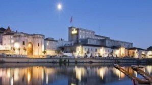 Ein Hotel am Wasser mit einem großen Gebäude und einem kleineren Bauwerk gegenüber.
