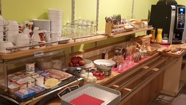 Ein reichhaltiges Frühstücksbuffet mit Speisen, Geschirr und einer Kaffeemaschine.