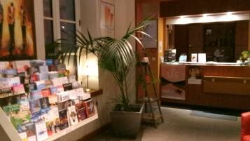 A reception area with a book display, a potted plant, and a counter.