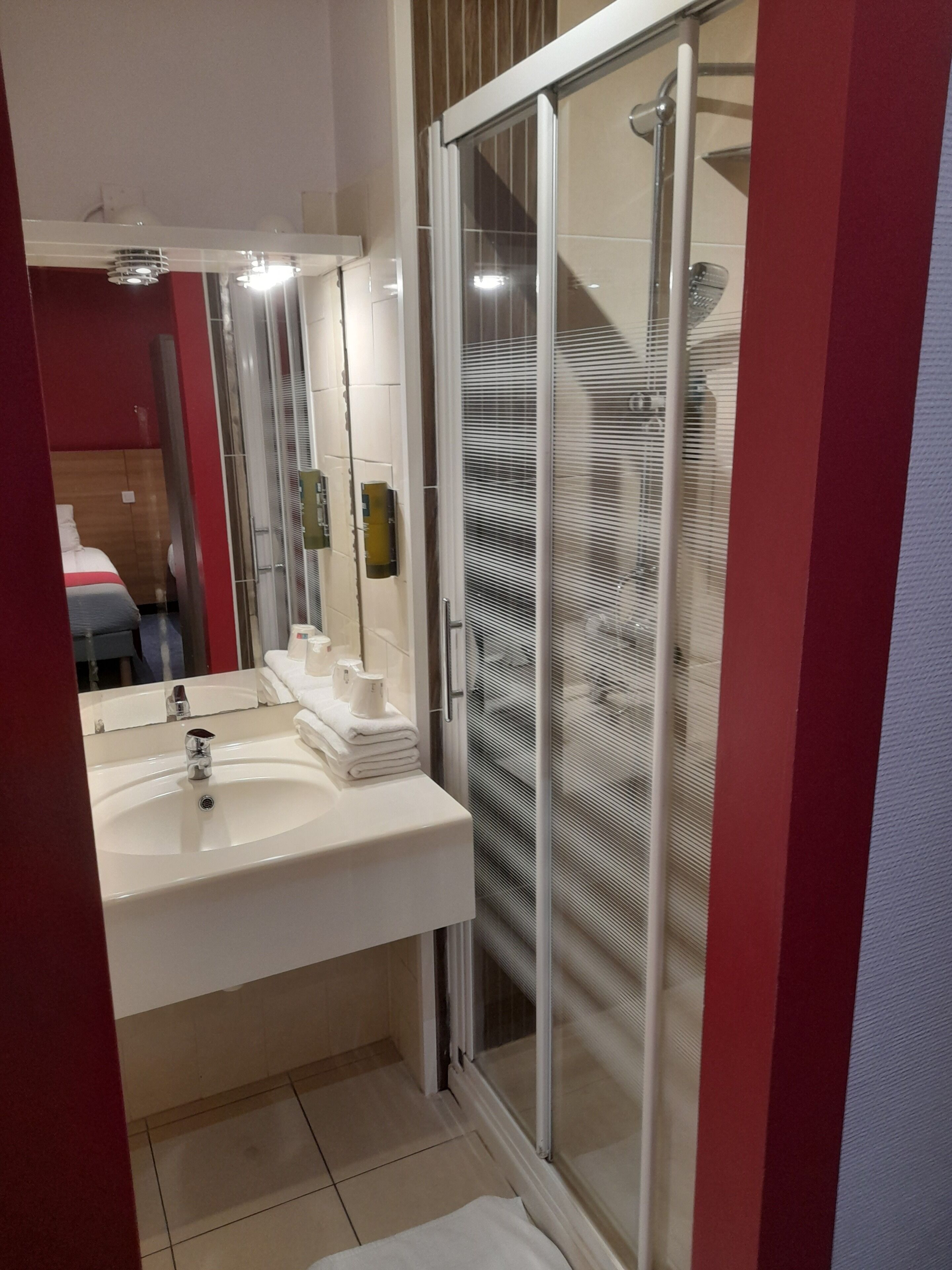 A modern bathroom with a white sink, a glass shower enclosure, and a mirror above the sink.