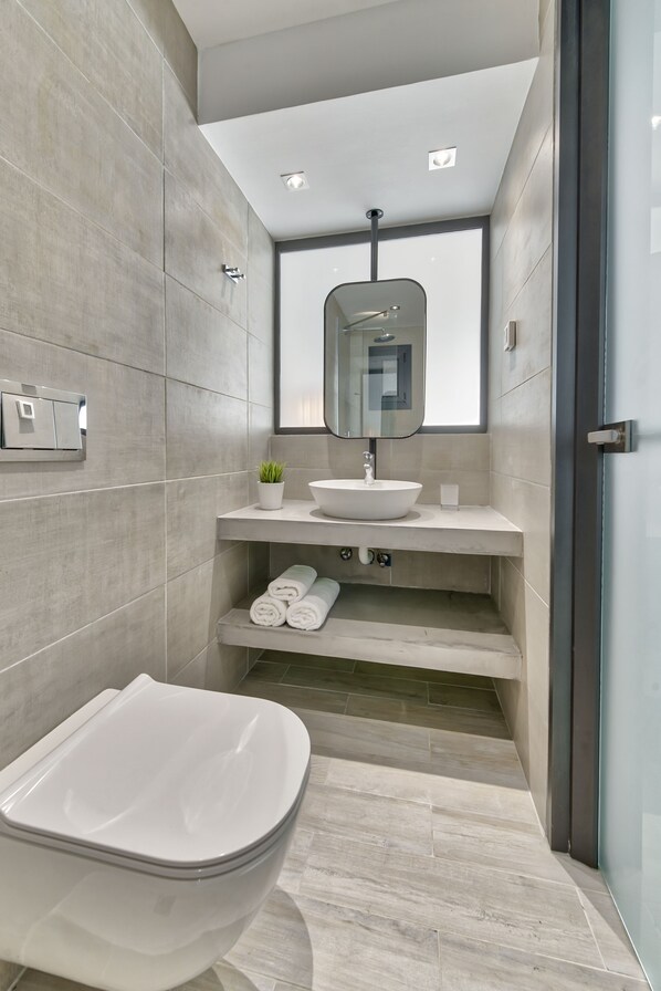 Un baño moderno con una bañera independiente, un lavamanos empotrado y un espejo grande.