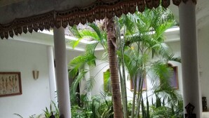 A courtyard with palm trees and a statue, surrounded by white columns and a patterned ceiling. - Diamond home 001 (Malindi)