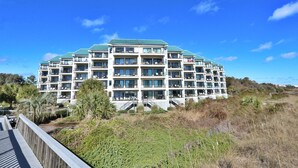 A multi-story hotel with balconies, a green roof, and a view of the surrounding landscape.