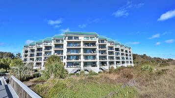 A multi-story hotel with balconies, a green roof, and a view of the surrounding landscape.