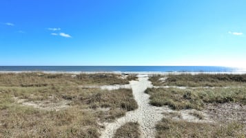 A beach path leading to the ocean with a clear sky.
