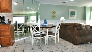 A dining area with a table and chairs, a brown sofa, and a kitchen area with cabinets and a stove.