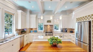A spacious kitchen with white cabinetry, a central island, and a large refrigerator.