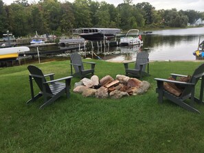 A lakeside deck with Adirondack chairs and a fire pit. - Spacious Lake Home Close To Notre Dame (Edwardsburg)