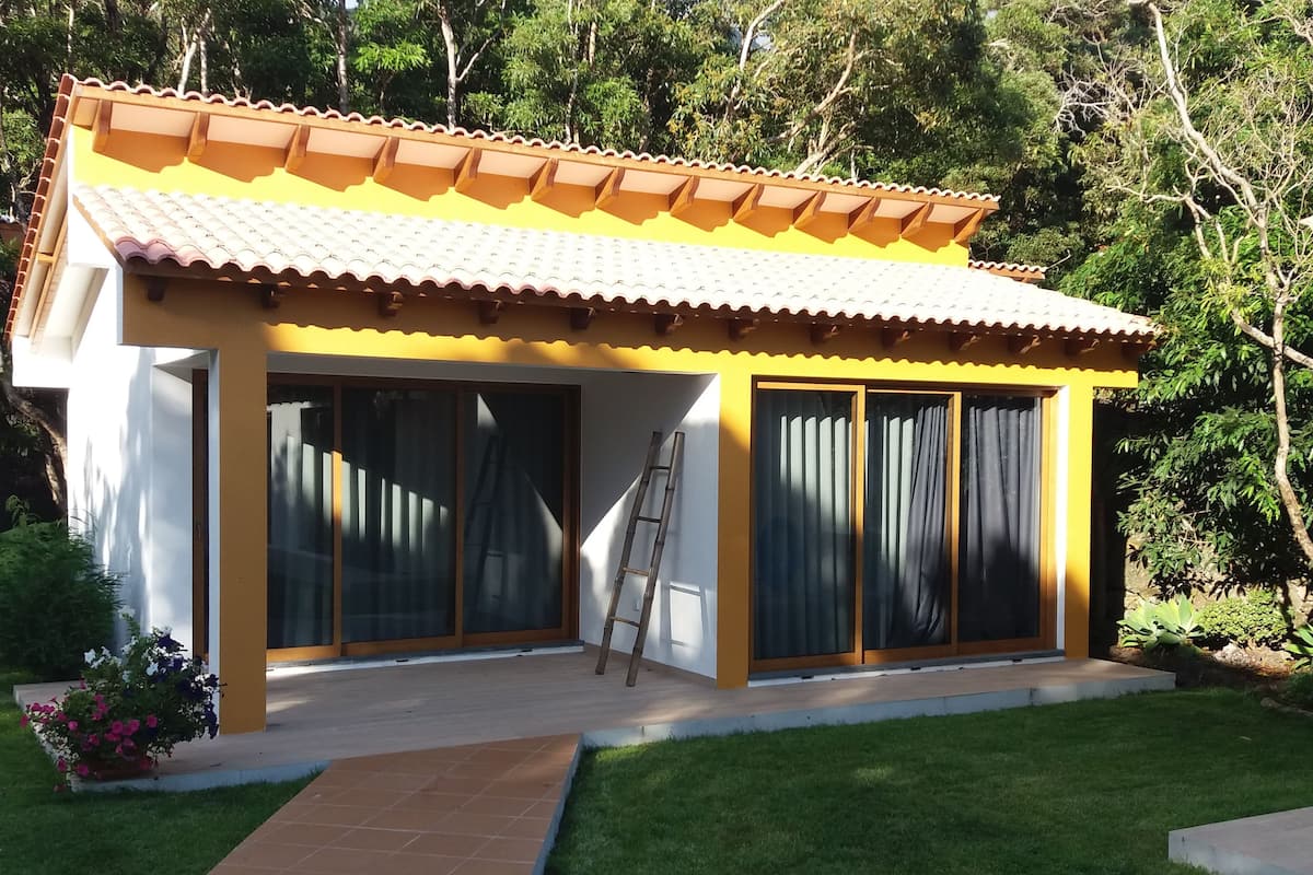 A small, yellow building with a tiled roof and large sliding glass doors.