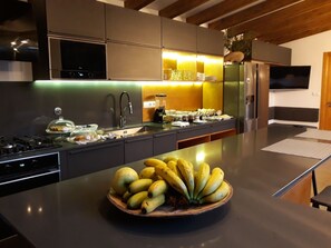 A modern kitchen with a central island, a built-in stove, and a refrigerator. - Villas Casteletes-bangalow Sea View (Velas)