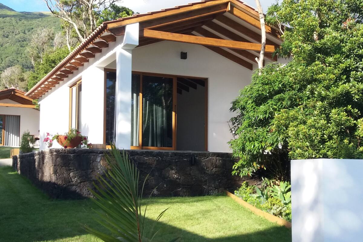 A modern house with a stone foundation, large windows, and a wooden roof.