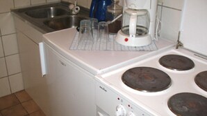 A kitchen with a white stove, a coffee maker, and a sink. - Haus am Cannstatter Wasen (Stuttgart)