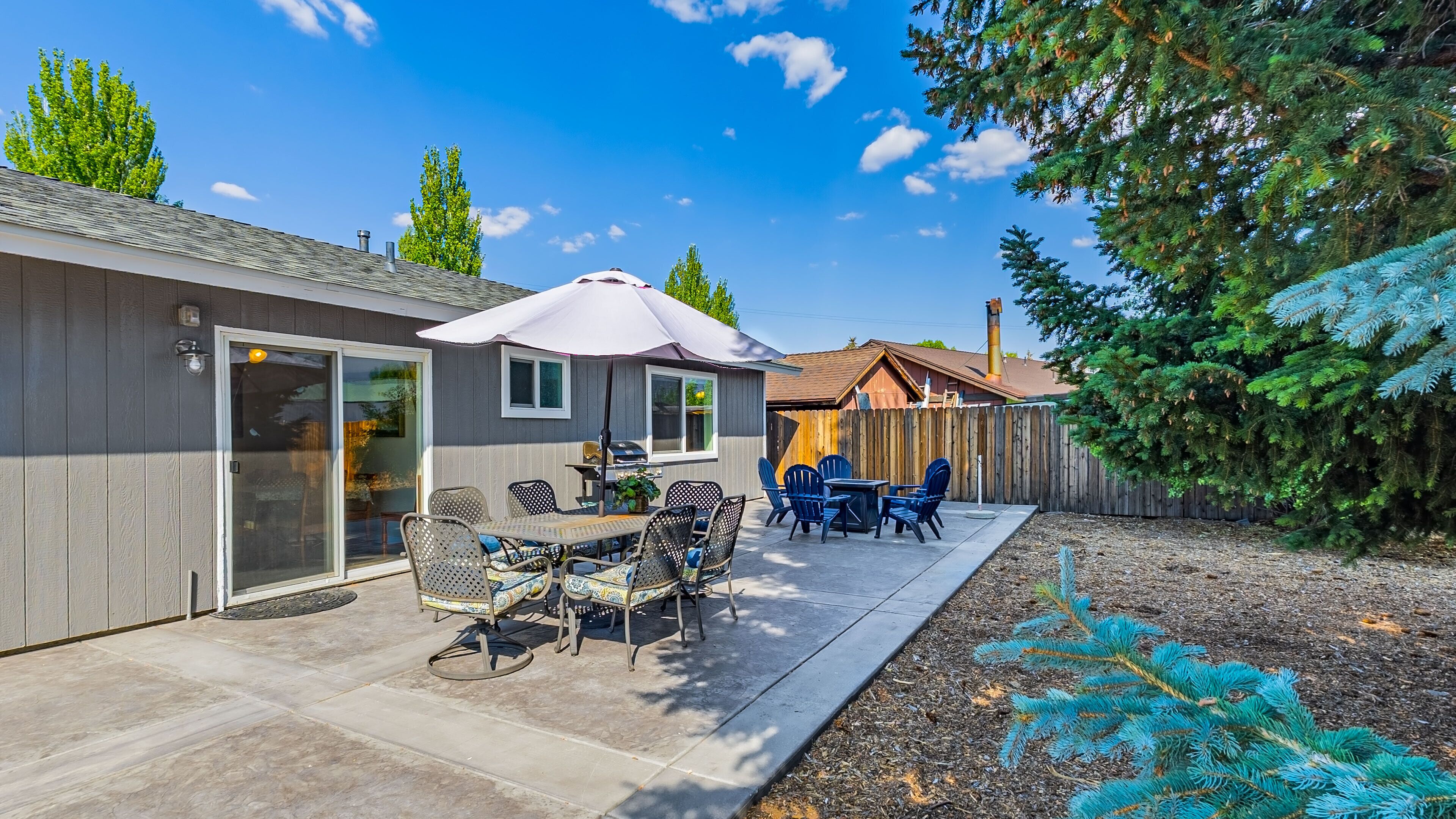 A patio with a table and chairs, a covered area, and a wooden fence.