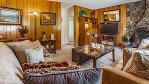 Un salón acogedor con chimenea, paneles de madera, televisor y asientos cómodos.