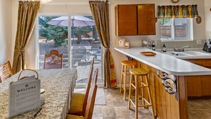 Una cocina con barra, taburetes de madera, un cartel de bienvenida y vistas al exterior.