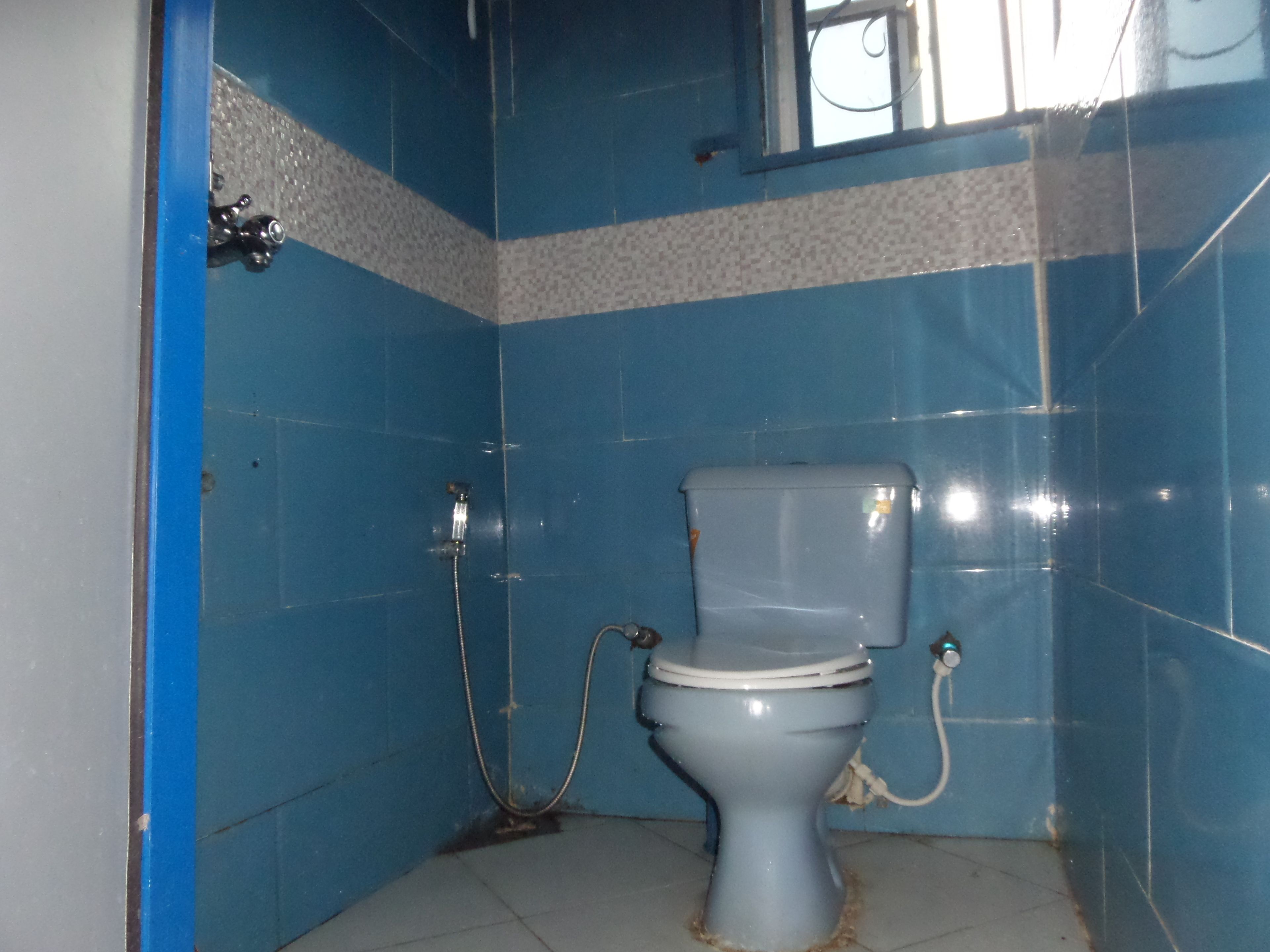 Un baño con inodoro, ducha y ventana.