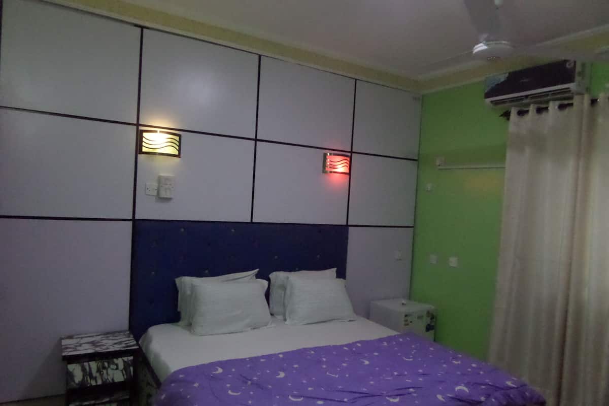 Een slaapkamer met een bed, nachtkastje en een airconditioning.