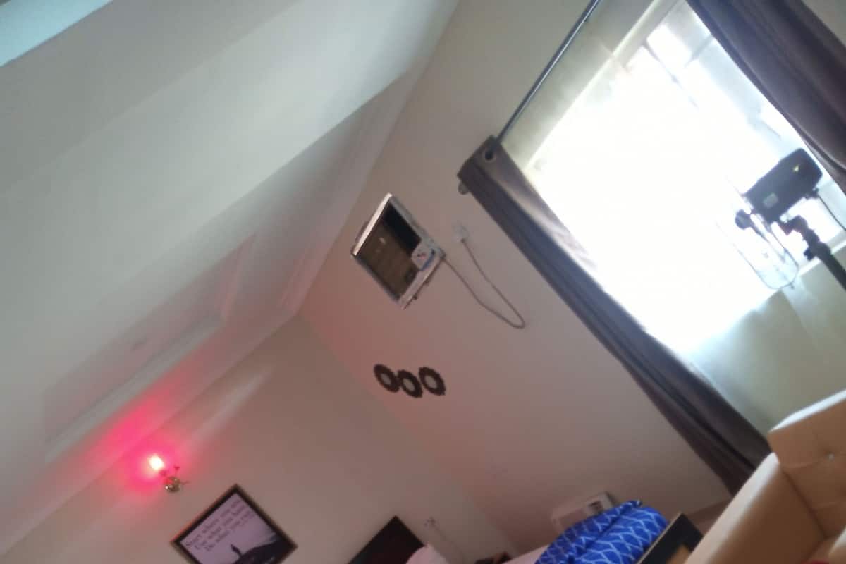Een hotelkamer met een bed, een klein raam en een aan de muur bevestigd telefoon.