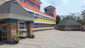 A hotel with a stone facade, a yellow and red building, and a covered area with a clock. - Jimson International Hotel and Suites (Abeokuta)