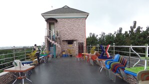 A rooftop terrace with a small brick building, outdoor seating with colorful chairs, and a staircase leading to an upper level. - Jimson International Hotel and Suites (Abeokuta)