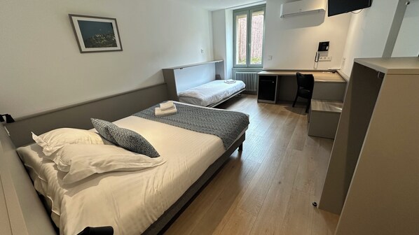 A bedroom with two beds, a desk, and a chair. - Hôtel du Fer à Cheval (Yenne)