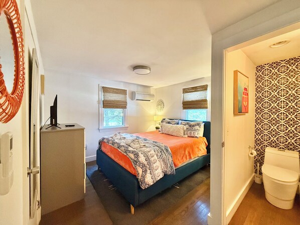 A bedroom with a bed, bedside table, and a window.