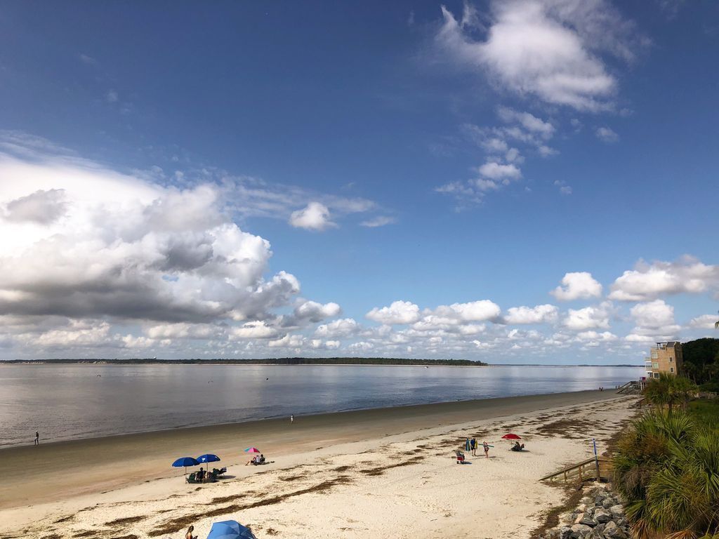 A beach with umbrellas, a sandy shore, and a calm sea.
