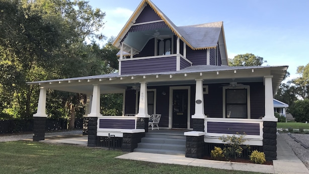 A two-story house with a porch, stone pillars, and a number plaque. - 1887 Royellou House 3BR 2BA (Mt Dora)