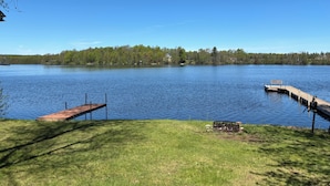 A lake with a dock extending into the water, surrounded by grassy areas and trees.