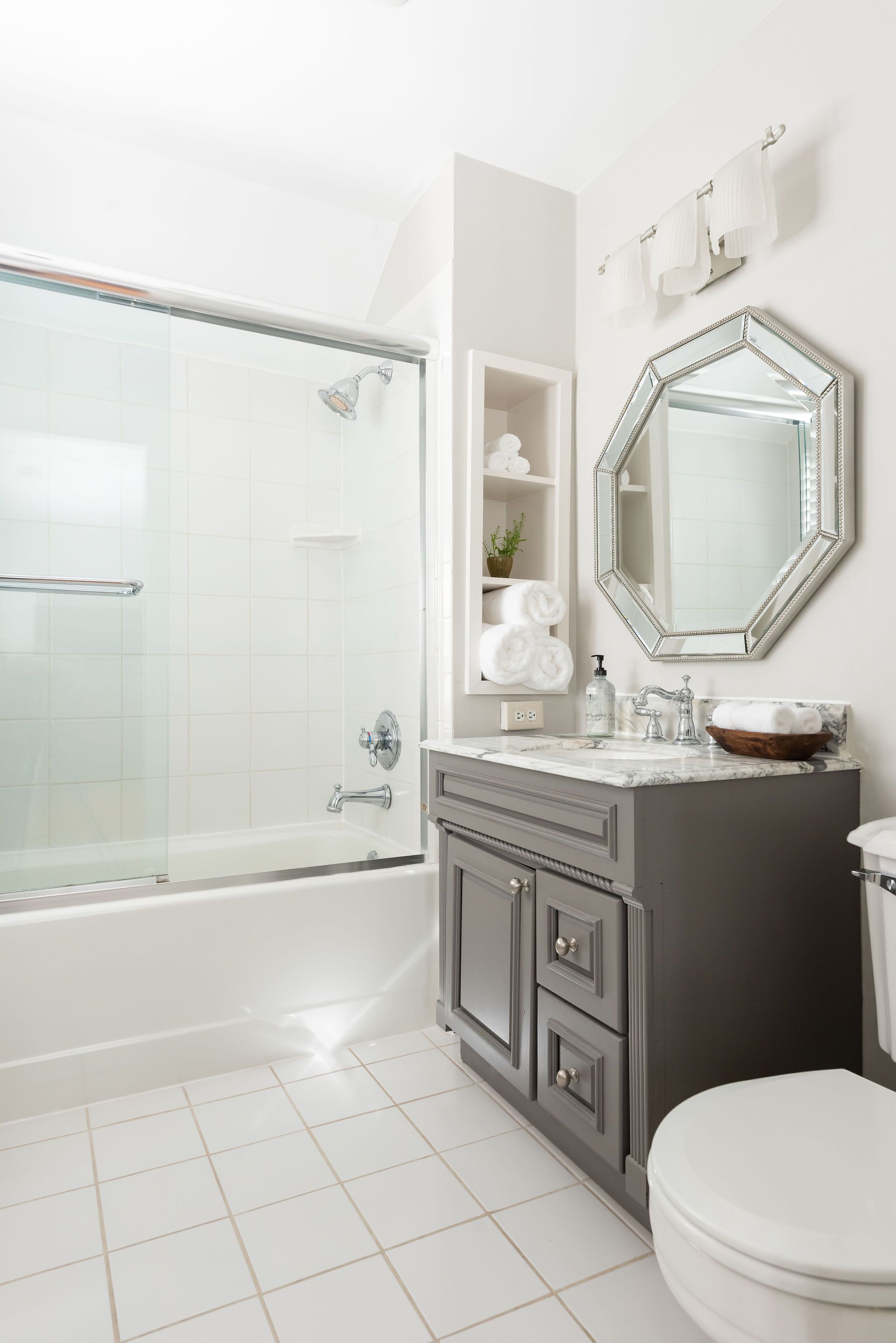 Une salle de bain moderne avec une douche à parois de verre, des toilettes blanches et un meuble-lavabo avec un miroir.