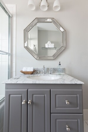 Een bad/douchecombinatie, een bubbelbad, een haardroger, handdoeken