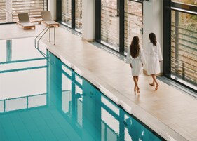 Zona de piscina con sillones de descanso y vista a la ciudad.