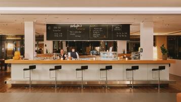A modern bar area with a central bar counter, stools, and a menu board displaying specials and prices.