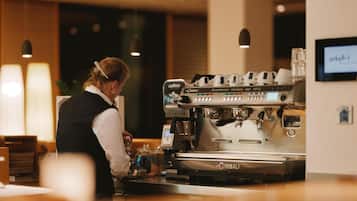 Een barista aan het werk achter een koffiemachine in een goed verlichte ruimte.
