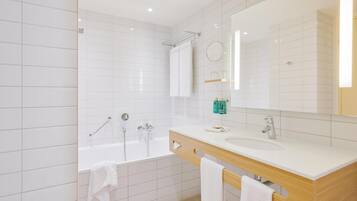Un baño moderno con una bañera blanca, un lavabo y un espejo grande.