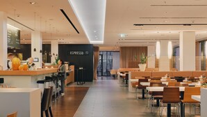 Un café moderno con barra, asientos y una estación de café espresso a la vista.