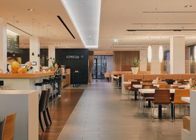 Un café moderno con barra, asientos y una estación de café espresso a la vista.