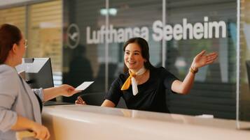 Ein Empfangstresen der Lufthansa Seeheim, wo eine Person ein Dokument an eine andere Person übergibt.